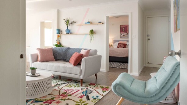 A modern living room with a sofa, a chair, and a coffee table. There are shelves with plants and decorative items on the wall. - Cosy 2-Bed Apartment in the Heart of Strathfield (Strathfield)