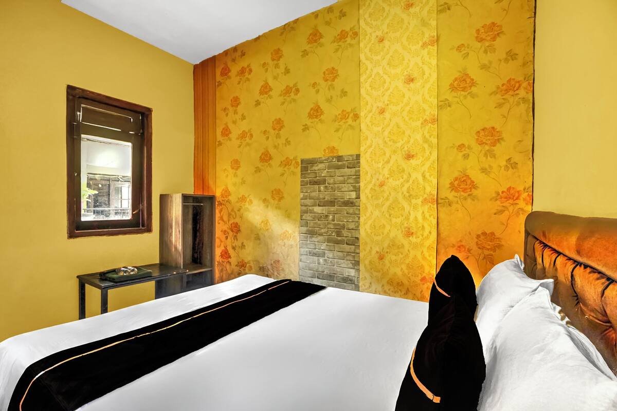 Une chambre d’hôtel avec un lit, une petite table, une télévision et une fenêtre.