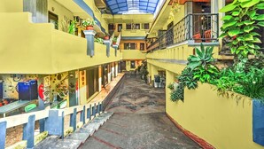 A multi-level atrium with a central staircase, balconies, and potted plants. - OYO 95043 Guest House Adel's (Malang)
