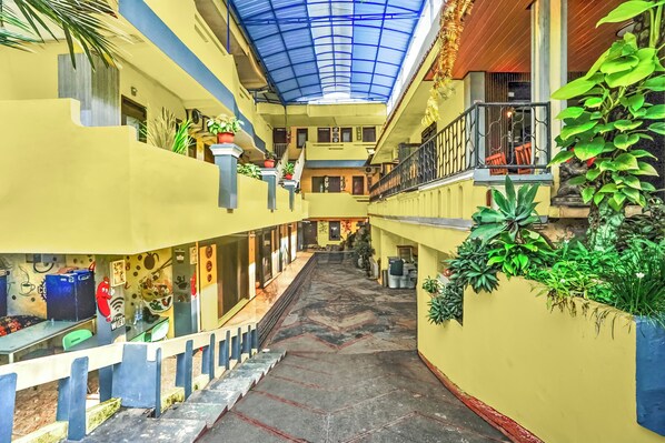 Un atrium à plusieurs niveaux, doté d’un escalier central, de balcons et de plantes en pot.