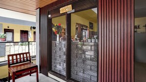 A reception area with a wooden bench, a 'Welcome' sign, and a glass door with a patterned design. - OYO 95043 Guest House Adel's (Malang)