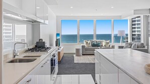 Una cocina moderna con vista al océano, un área de comedor con sofá y un ventanal grande.