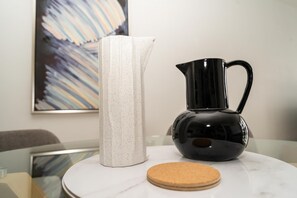 Eine weiße Vase und eine schwarze Karaffe auf einem Glastisch.