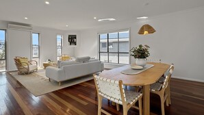 Un ampio soggiorno con zona pranzo, ampie finestre e un moderno design del soffitto.