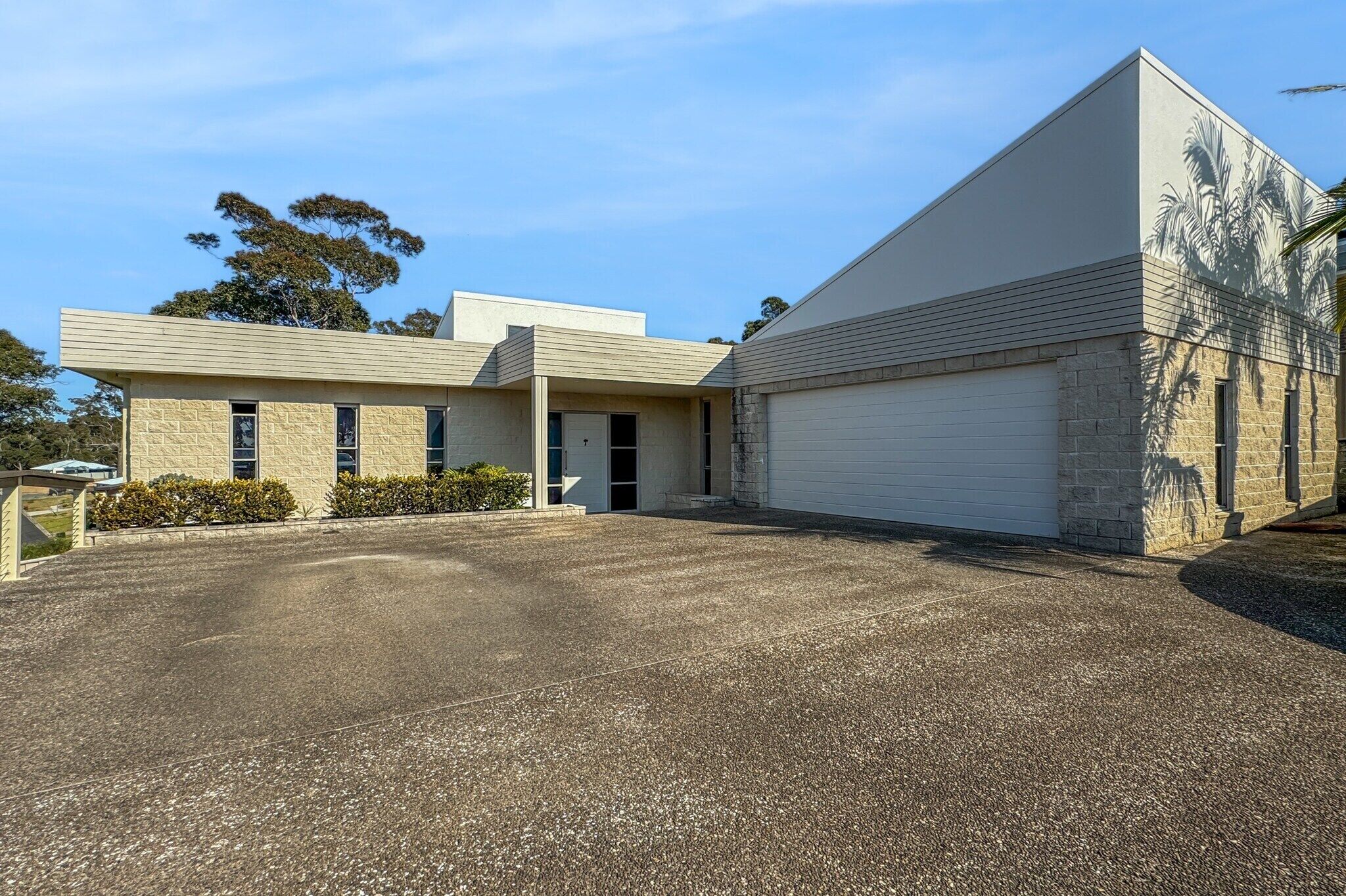 A modern two-story house with a garage, a driveway, and a landscaped front yard.