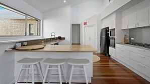 Una cucina moderna con isola in legno, sgabelli da bar bianchi e una grande finestra.