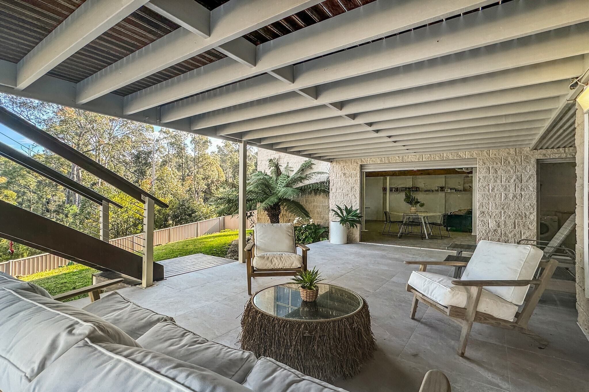 An outdoor patio area with a sofa, chairs, and a round table.