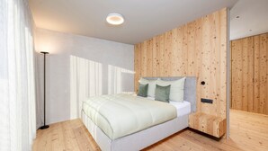 Une chambre à coucher moderne avec un plancher en bois, un lit doté d’une tête de lit blanche et une table de chevet.