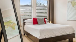 A neatly made bed with white bedding and two pillows, a world map on the wall, and a window with blinds. - Stunning 2-Bed Unit with BBQ Patio near Dining (Northcote)