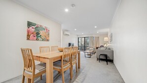 Una sala moderna con una mesa de comedor de madera, sillas, un sofá y un televisor.