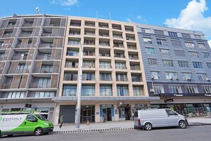 A multi-story building with balconies, a convenience store, and a Domino's pizza restaurant. - Central 1-Bedroom Apartment with City Views (Surry Hills)