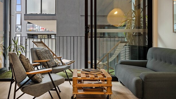 A modern living room with a sofa, armchairs, a coffee table, and a view of a balcony. - City View Haven in South Melbourne (South Melbourne)