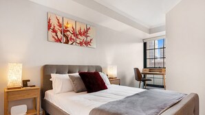 Habitación de hotel con una cama grande, dos mesitas de noche, un escritorio y una ventana.