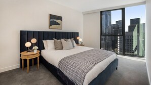 Een moderne slaapkamer met een groot bed, uitzicht op de stad en een lijst met een kunstwerk aan de muur.