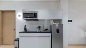 Une cuisine moderne avec des meubles blancs, un four à micro-ondes en acier inoxydable et un réfrigérateur.