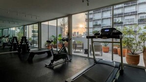 Et fitnesscenter med træningsudstyr, store vinduer og plantekasser.