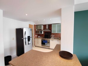 Eine kleine Küche mit Kühlschrank, Mikrowelle, Herd und Schränken.