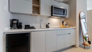 A modern kitchen with white cabinetry, a black refrigerator, a microwave, and a coffee maker. - TOP Condesa Loft | Chic Studio (Mexico City)