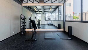 A gym with exercise equipment, a treadmill, and a large window offering a city view. - TOP Condesa Loft | Chic Studio (Mexico City)