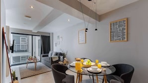 A modern dining area with a glass table, dark chairs, and a breakfast setting including plates, bowls, and orange juice. - TOP Condesa Loft | Chic Studio (Mexico City)