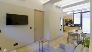 Un saló modern amb televisió de pantalla plana, una taula petita i un sofà.
