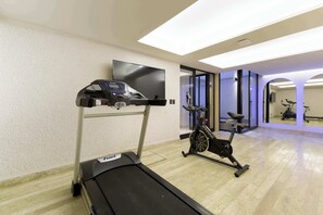 A gym with a treadmill, stationary bike, and a TV mounted on the wall. - TOP Homero - Modern 1BR apartment (Mexico City)