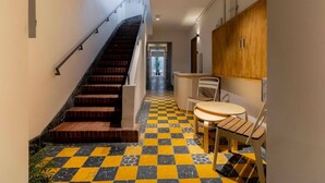 Ein Flur mit Schachbrettfußboden, einer Treppe, einem Tisch mit Stühlen und einem Holzschrank.