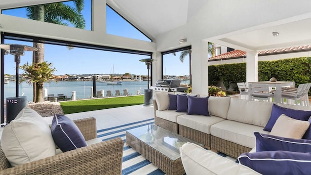 Una zona relax esterna moderna con vista sull'acqua, dotata di barbecue e comodi posti a sedere.