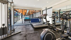 Une salle de sport moderne équipée de machines de cardio, d’appareils de musculation et dotée d’une grande fenêtre offrant une vue sur l’extérieur.