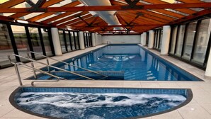 Une piscine intérieure dotée d’un plafond en bois et de murs en verre.