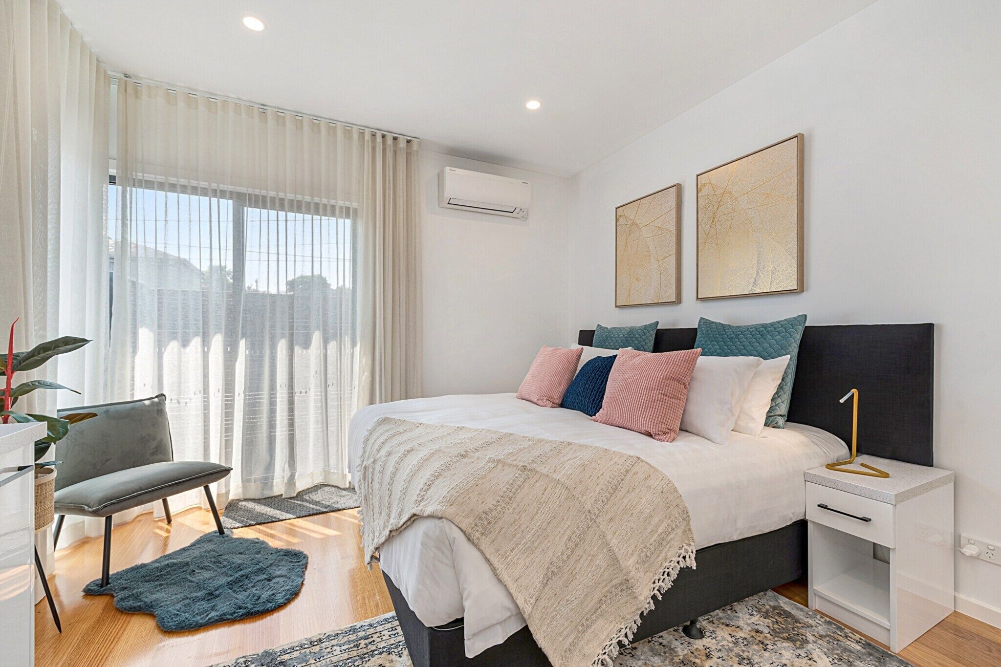 Une chambre moderne avec un lit, des tables de chevet, une chaise et une fenêtre avec des rideaux.