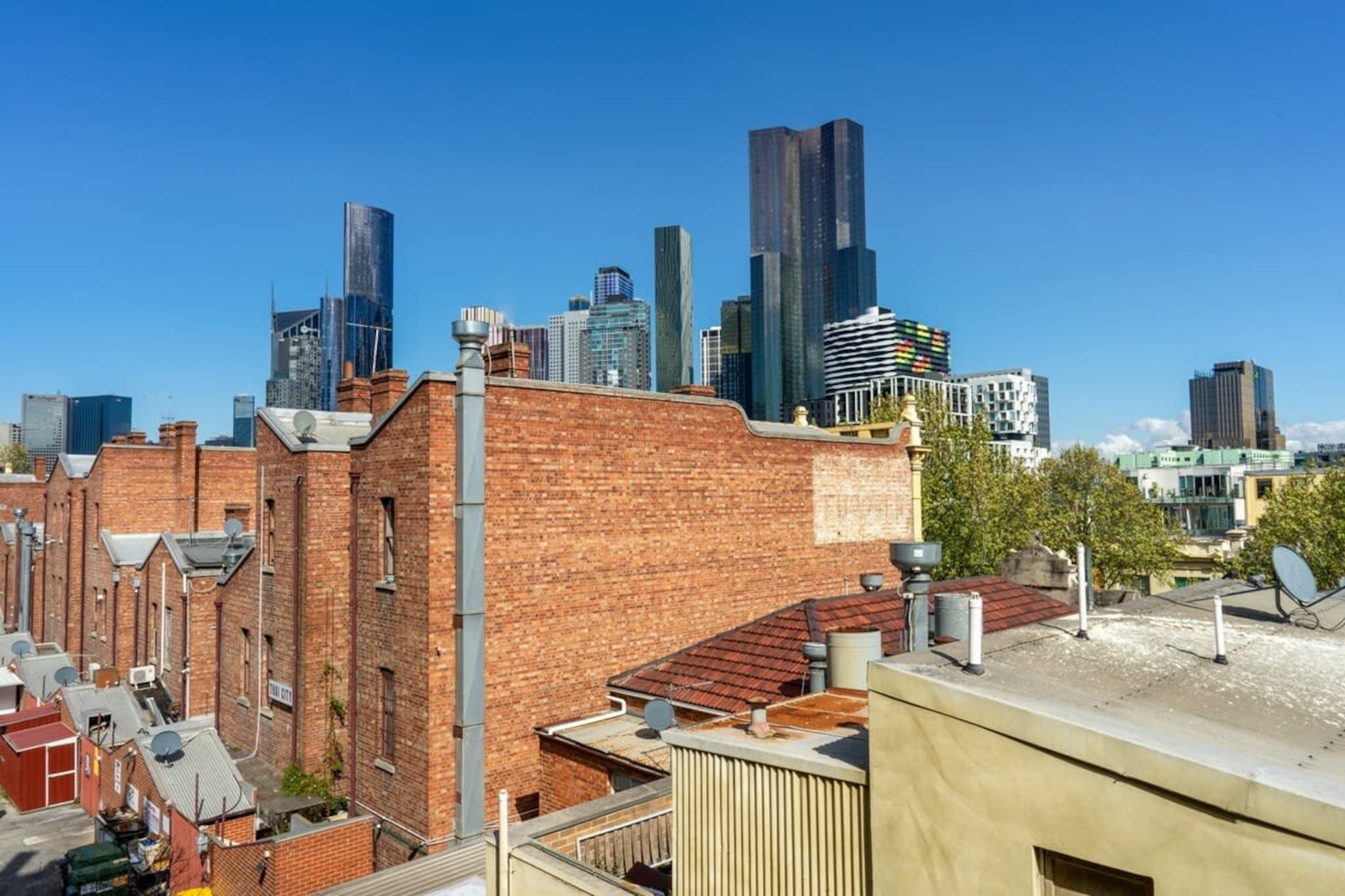 A cityscape with modern high-rise buildings and a brick building in the foreground.