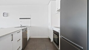A modern kitchen with white cabinetry, a stainless steel refrigerator, a dishwasher, and a tiled backsplash. - Executive and Spacious Apartment with Balcony (Sunshine)