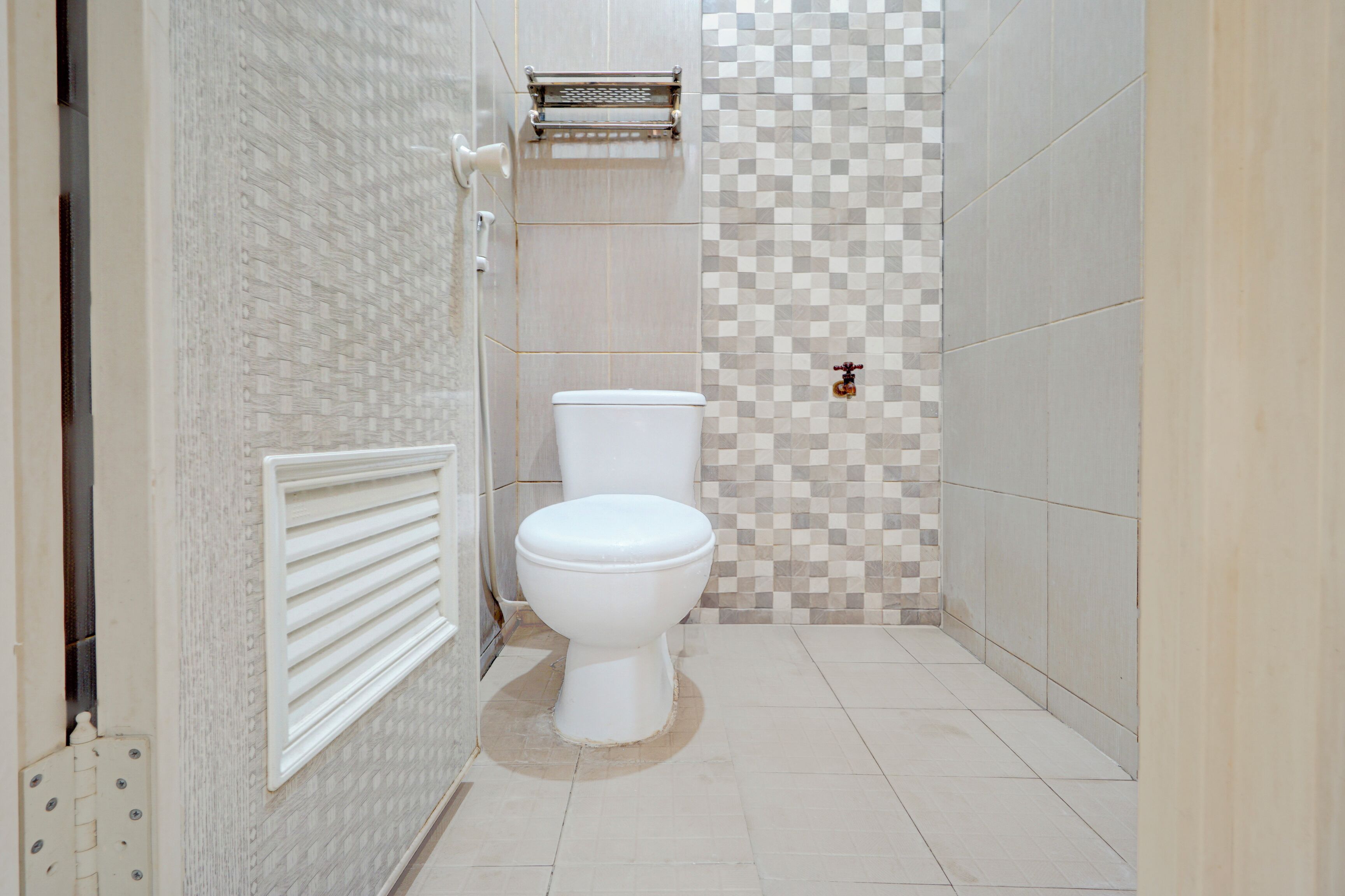 Un baño con inodoro, ducha y pared con azulejos.