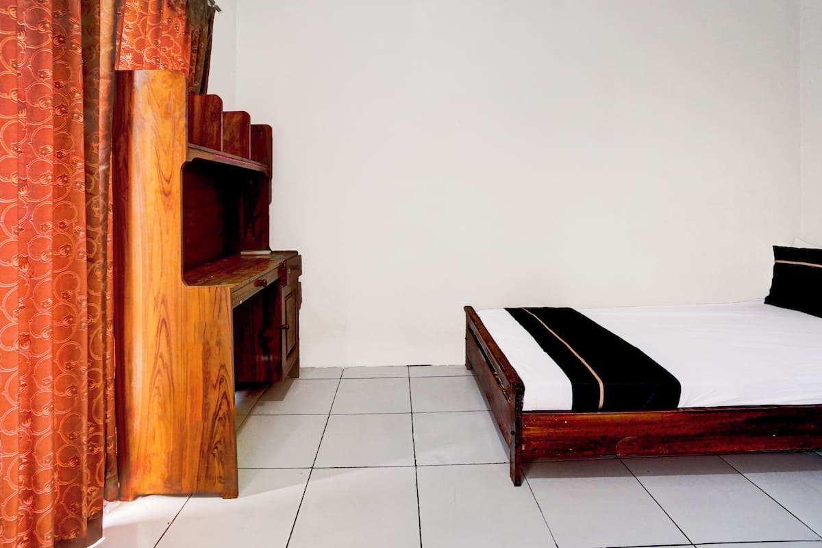 Une chambre à coucher avec un lit en bois, une table de chevet et une armoire en bois.