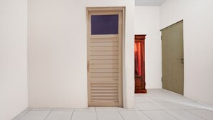 Un couloir avec une porte fermée, une porte entrouverte avec un rideau rouge, et une porte fermée avec un cadre en bois.