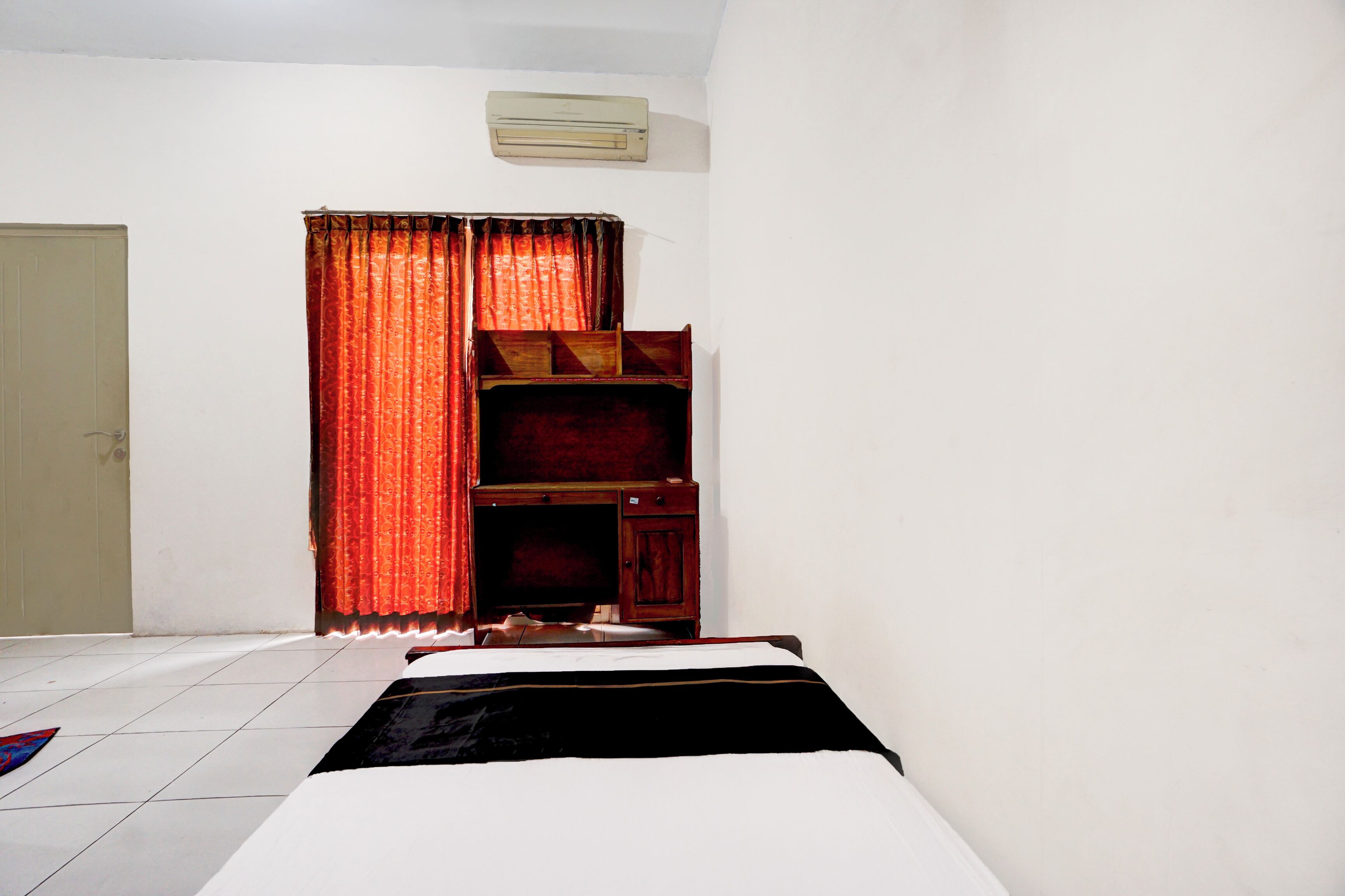 A room with a bed, a wooden cabinet, and a curtain.