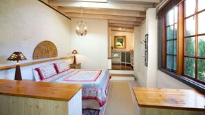 Un dormitorio acogedor con cabecera de madera, una cama grande con ropa de cama estampada, una araña y vistas por la ventana.