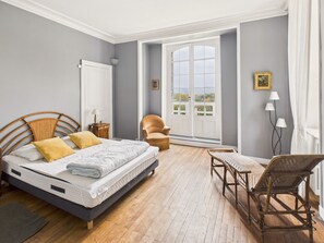 A bedroom with a bed, a chair, a table, a window, and a door. - Manor with Terrace and Pool for 12 Guests (Saint-Léon-sur-Vézère)