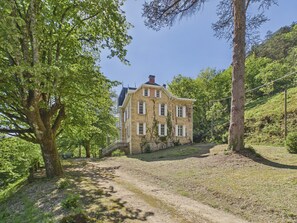 A stone building with a sloped roof, surrounded by trees and a dirt path. - Manor with Terrace and Pool for 12 Guests (Saint-Léon-sur-Vézère)