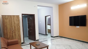 Un salon avec un canapé, une table basse, un téléviseur et une armoire.
