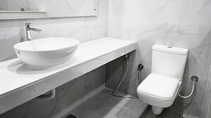Une salle de bain avec un lavabo en marbre blanc, des toilettes et un miroir au-dessus du lavabo.