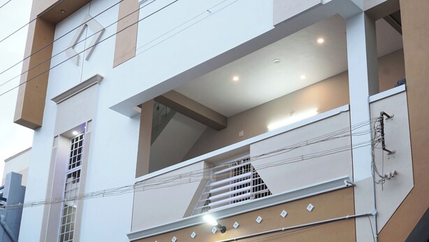 Un immeuble à plusieurs étages doté d’une architecture moderne, comprenant un escalier central, des balcons et une entrée sécurisée par un portail.