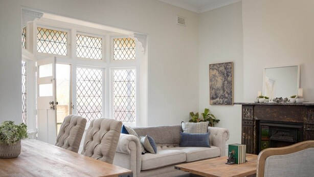 A living room with a sofa, a coffee table, and a fireplace. There is a dining table with chairs and a rug. - Central 2-Bed Apartment with Private Parking (Strathfield)