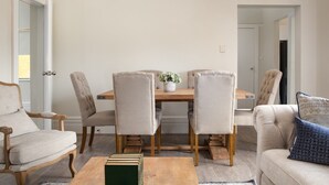 A living room with a dining table, four chairs, a sofa, and a coffee table. - Central 2-Bed Apartment with Private Parking (Strathfield)