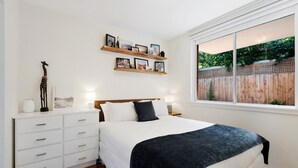 Une chambre à coucher avec un lit, une commode blanche et des étagères ornées de photos encadrées.