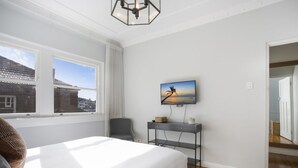 Un dormitorio con cama, televisor en la pared, escritorio y una silla.