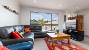 A modern living room with a leather sofa, a wooden coffee table, and a red rug. - Spacious and Restful Holiday Home with Backyard (Cook)