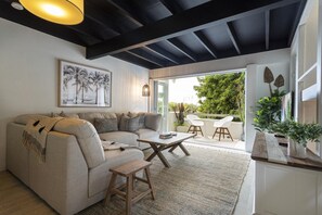 Een moderne woonkamer met een bank, salontafel en een eethoek met stoelen.