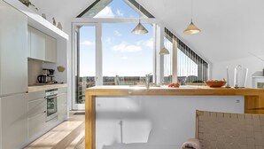 A modern kitchen with a large island, white cabinetry, and a view through a skylight. - "Saxi" - 650m from the sea by Interhome (Skagen)